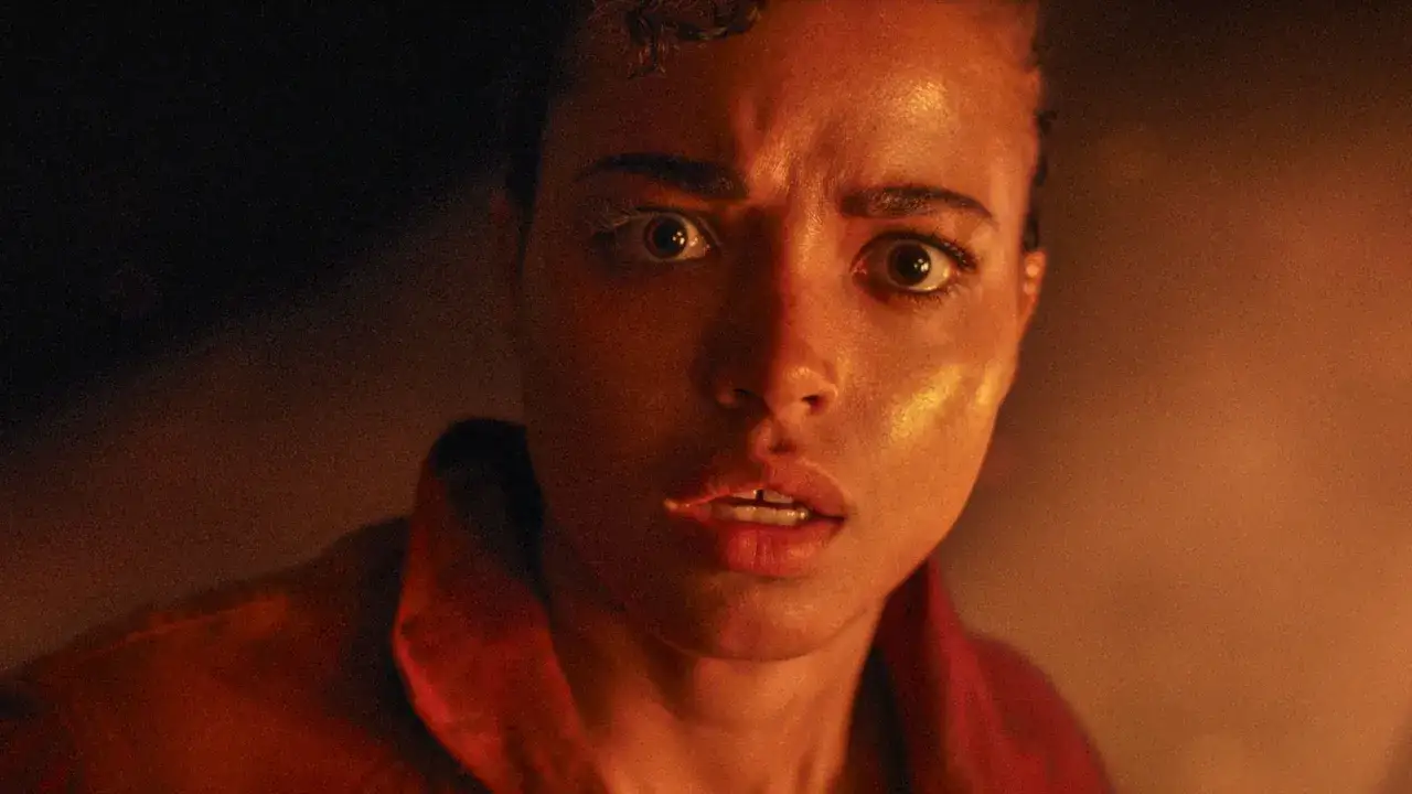 Przerażona twarz kobiety w czerwonej kurtce, oczy szeroko otwarte. Scena z Resident Evil: Remedium.