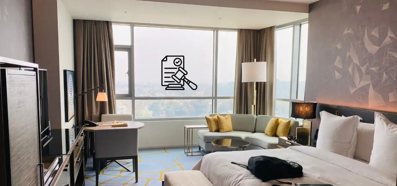 Wygodne łóżko, sofa i biurko w hotelowym pokoju. Ikona dokumentu z młotkiem sugeruje, że wiek zameldowania w hotelu jest regulowany prawnie.