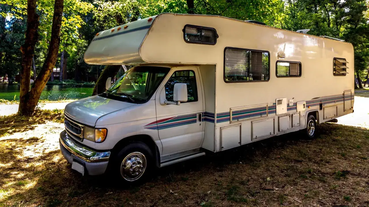 Kamper kat C zaparkowany w lesie, gotowy na przygodę nad jeziorem.