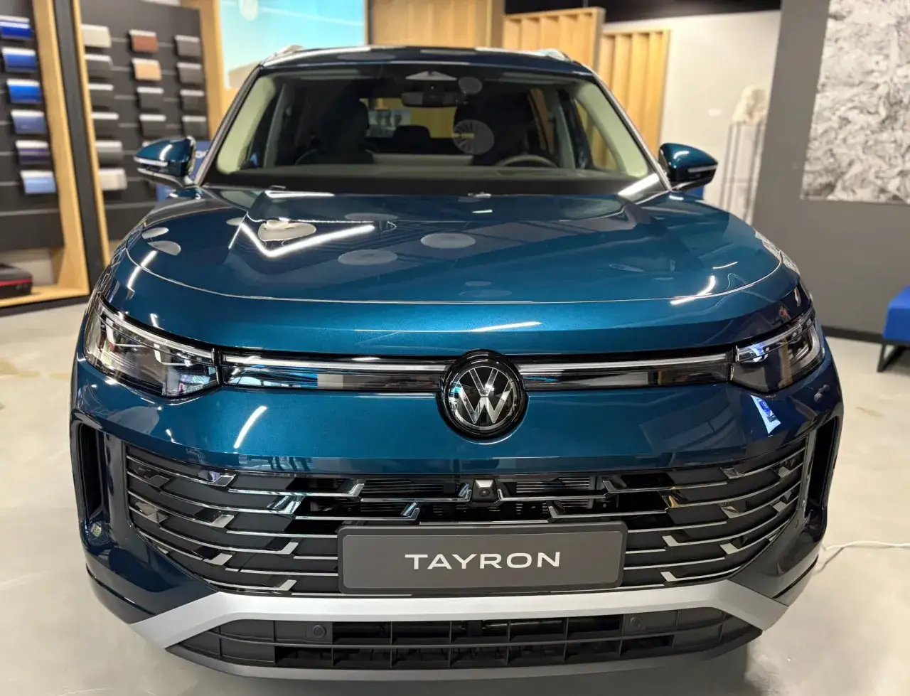 Błękitny Volkswagen Tayron z błyszczącym grillem i logo VW.