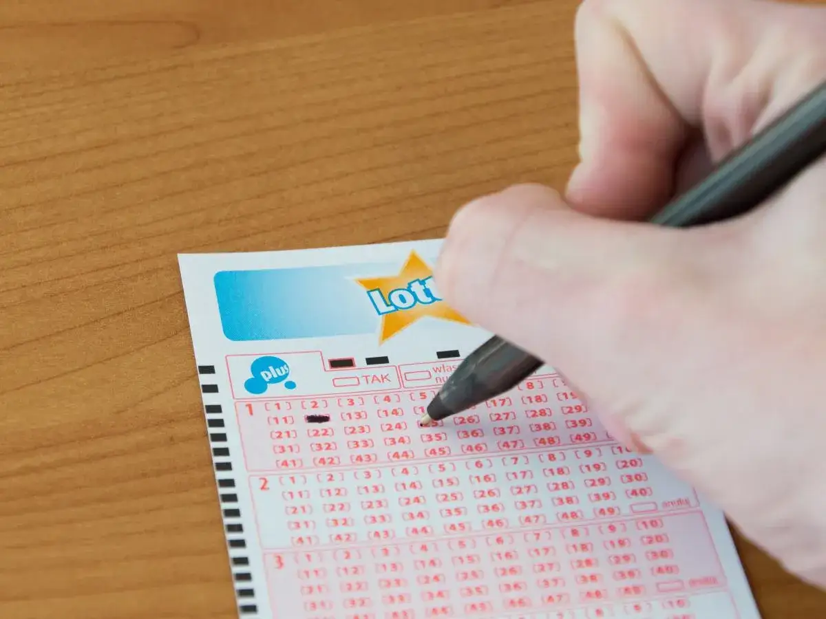 Ręka zaznacza liczby na kuponie lotto, marząc o wygranej w jackpot.