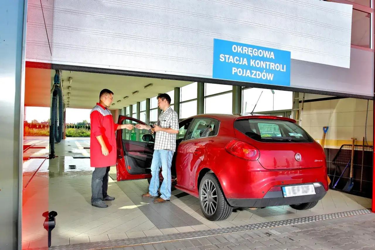 Pracownik stacji kontroli pojazdów przekazuje kluczyki kierowcy czerwonego Fiata Bravo. Dowiadujemy się, ile kosztuje przegląd techniczny samochodu.