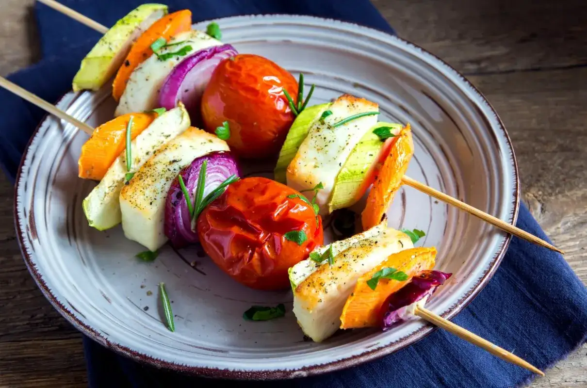 Kolorowe przystawki na grilla: szaszłyki z halloumi, pomidorkami, cukinią, czerwoną cebulą i papryką, doprawione ziołami.