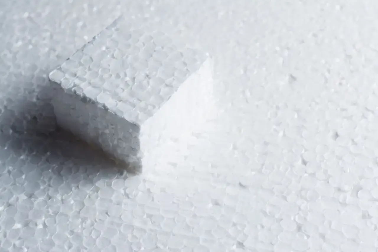 Biały sześcian z ekspandowanego polistyrenu na tle drobnych kuleczek. Czy to styrobeton czy styropian?