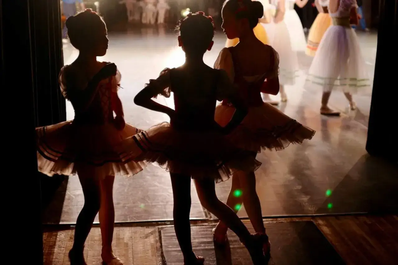 Trzy małe baletnice w tiulowych sp&oacute;dniczkach czekają na scenie. Ich zabawy taneczne dla dzieci wkr&oacute;tce się rozpoczną.