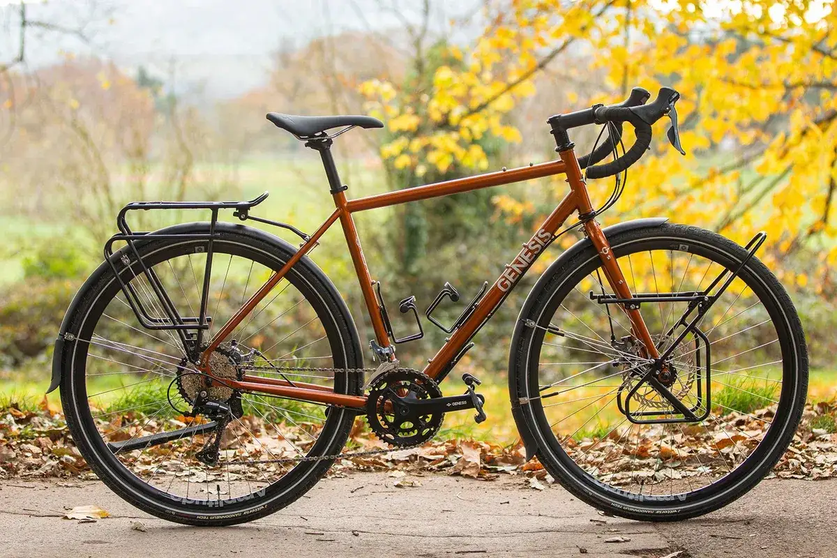 Pomarańczowy rower Genesis z bagażnikami, idealny jako rower na długie trasy. Gotowy na przygodę!