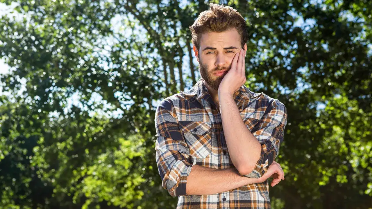 Zamyślony mężczyzna w kratę zastanawia się, jak napisać przeprosiny.