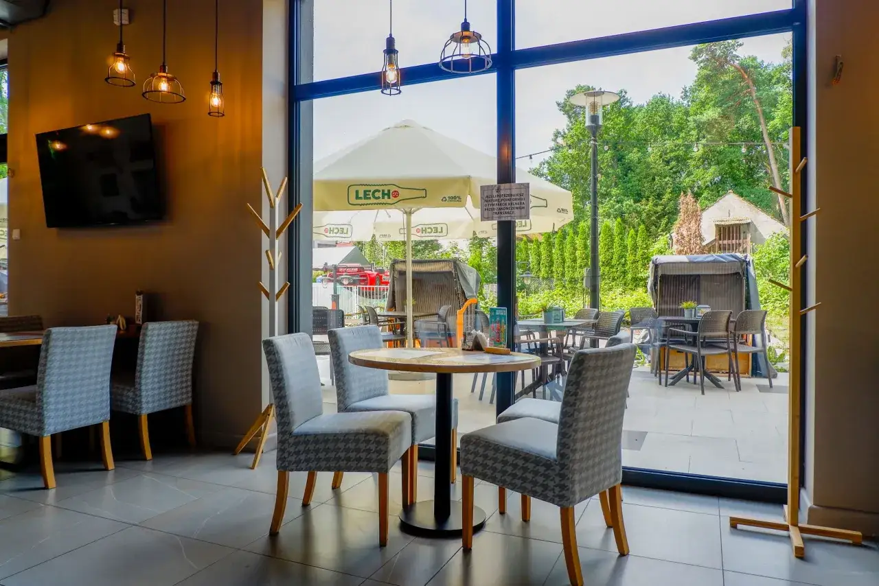 Przytulne wnętrze restauracji z widokiem na ogr&oacute;d. Idealne miejsce, by dowiedzieć się, gdzie zjeść w Niechorzu.