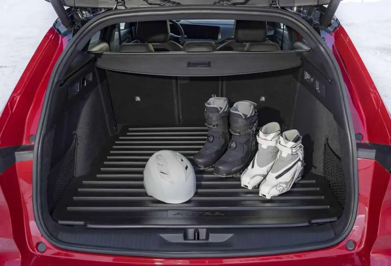 Bagażnik Opla Astry gotowy na zimowe szaleństwo. Kask i buty narciarskie czekają na wyjazd. Który Opel jest najlepszy? Ten, który zabierze Cię wszędzie!