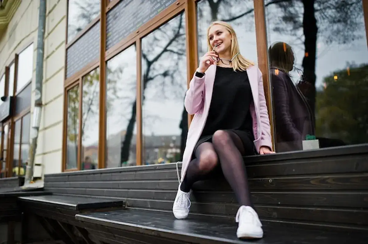 kobieta w stylowej casualowej stylizacji z czarnymi legginsami i swetrem oversize idąca ulicą miasta