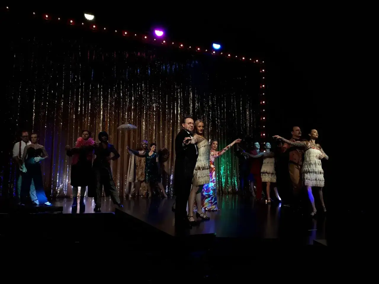 Scena teatralna z tancerzami w strojach z epoki. W centrum para, a obok niej żołnierz królowej Madagaskaru.