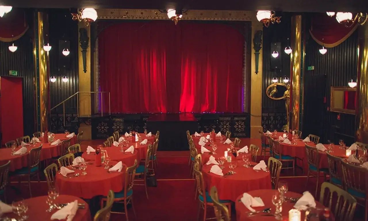 Elegancka sala Teatru Sabat z czerwonymi obrusami i sceną. Zastanawiasz się, ile kosztuje bilet do teatru Sabat?