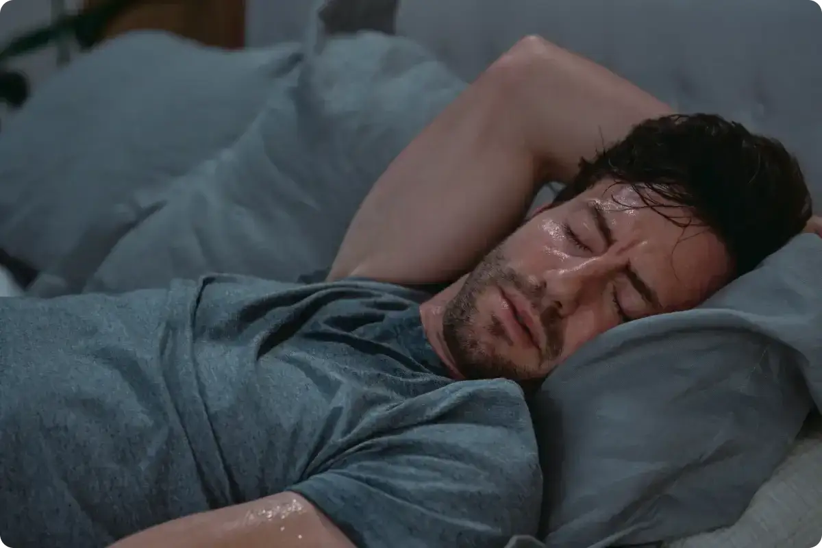 Mężczyzna śpi, jego ciało pokryte jest potem. To niepokojące pocenie się w nocy bez gorączki.