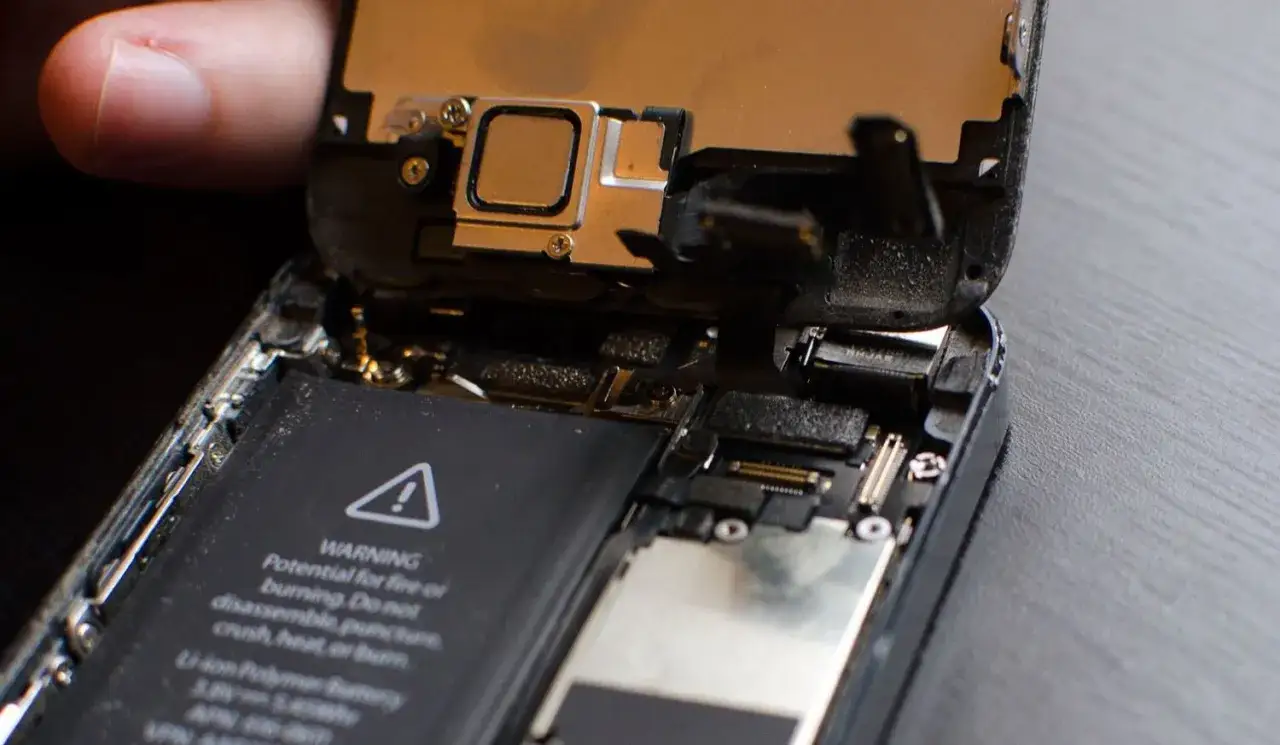 Rozkręcony telefon, widać baterię i elementy, które mogą być przyczyną, dlaczego głośnik w telefonie trzeszczy.