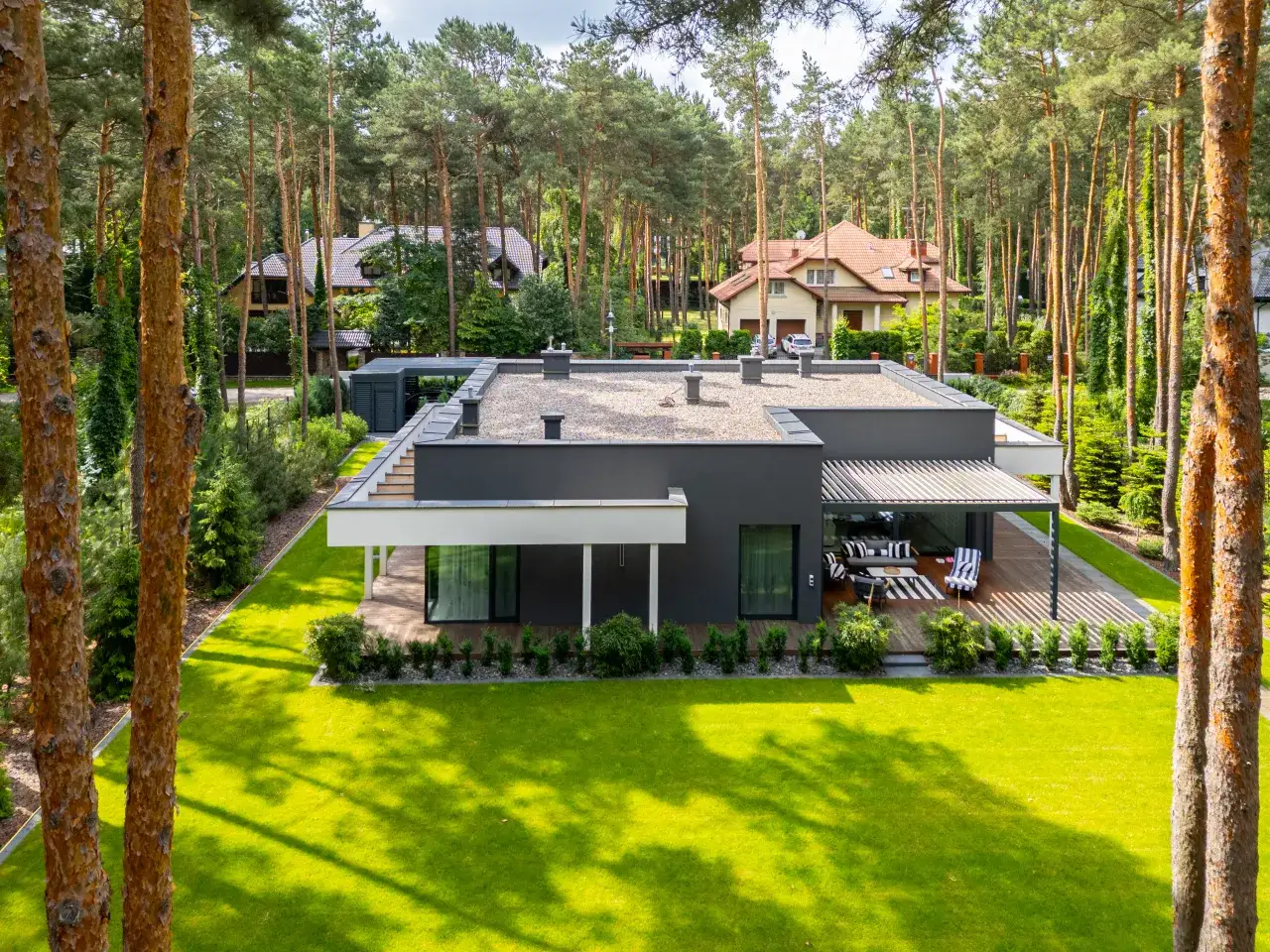 Nowoczesny dom z płaskim dachem, otoczony lasem sosnowym. Idealny przykład, jak zbudować dom w harmonii z naturą.
