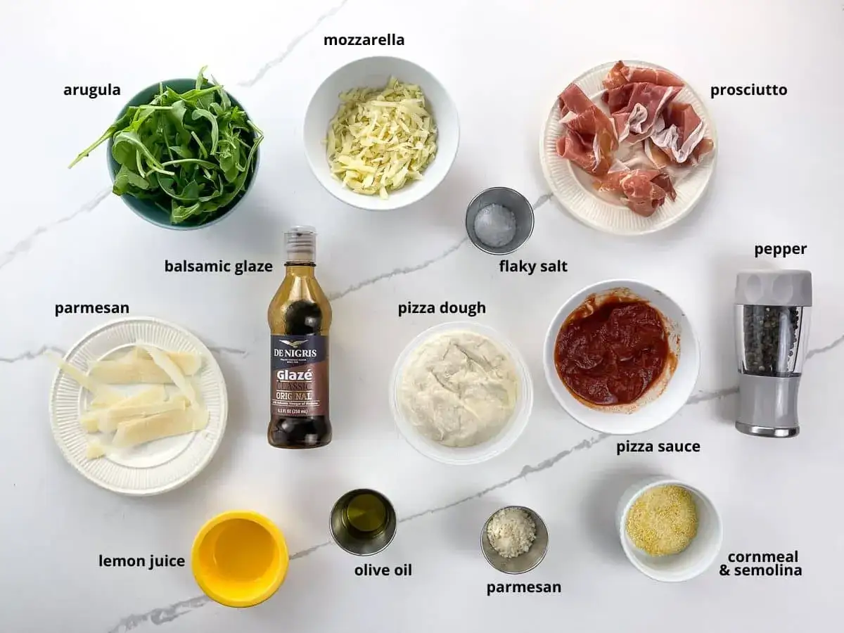 Składniki na pizzę z rukolą: ciasto, sos, mozzarella, prosciutto, parmezan, rukola, oliwa, cytryna, balsamico, s&oacute;l, pieprz.