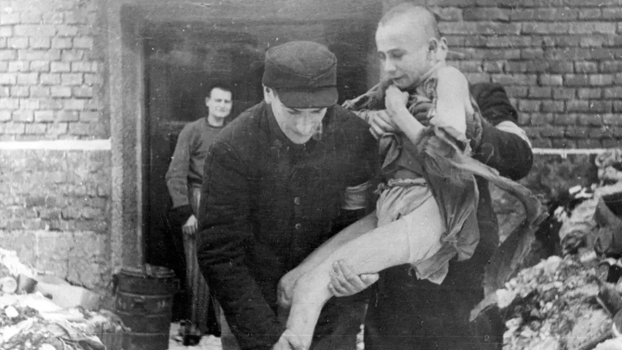 Oswobodzony chłopiec z Auschwitz, niesiony przez żołnierza. Obraz ten jest świadectwem okrucieństwa, o kt&oacute;rym opowiadają książki o Auschwitz.