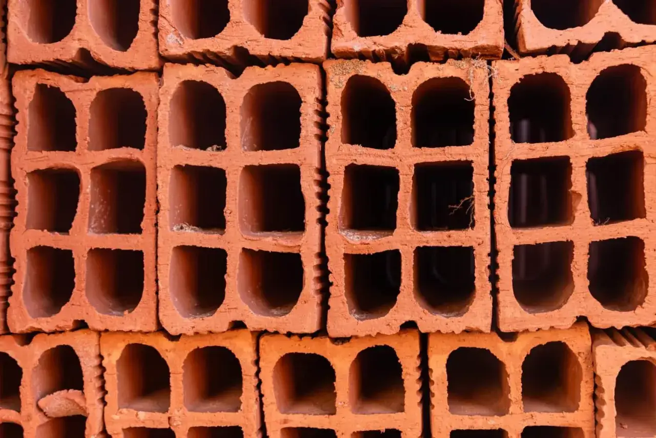 Stos pustaków ceramicznych, gotowych do budowy domu. Cegły z licznymi otworami, tworzące solidną bazę dla przyszłych ścian.