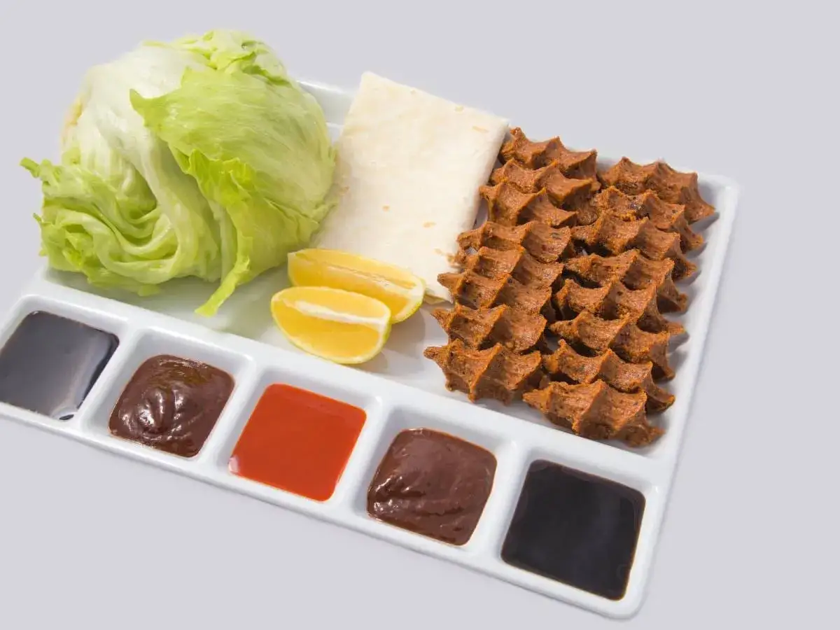 Talerz z sałatą, cytryną, tortillą i kilkoma sosami, w tym oryginalny turecki sos do kebaba.