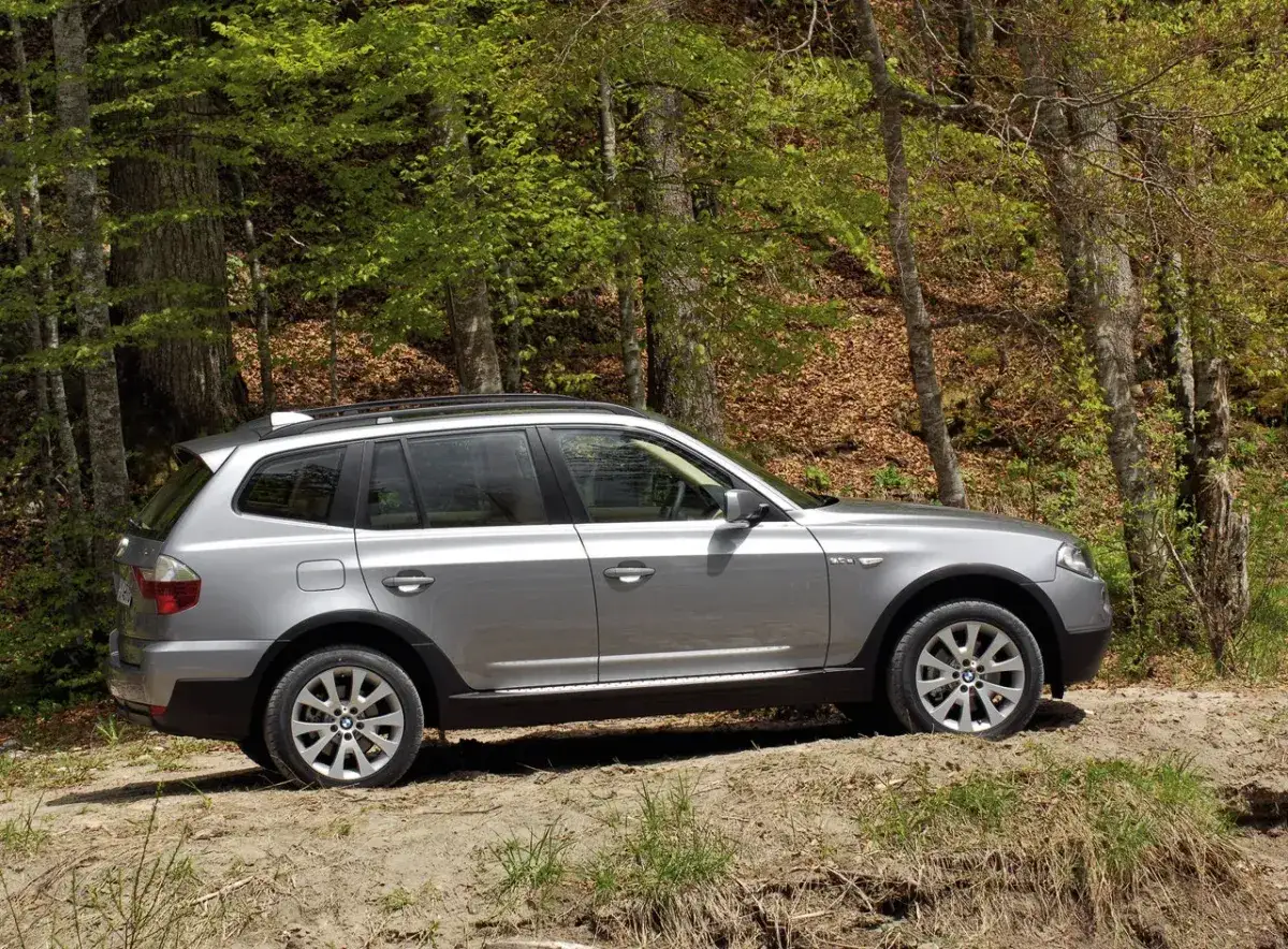 Srebrne BMW X3 E83 na leśnej ścieżce, gotowe na przygodę wśród zieleni.