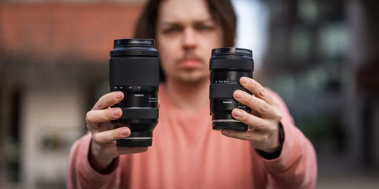 Mężczyzna prezentuje dwa obiektywy Tamron: jeden 70-180mm, drugi 17-50mm.