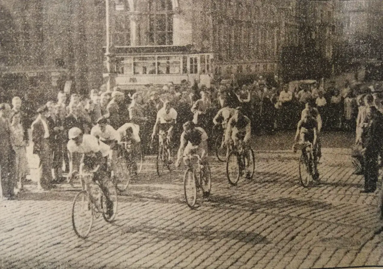 Wyścig kolarski na brukowanej ulicy, tłum kibic&oacute;w, tramwaj w tle. To widok na dawny rower w akcji.