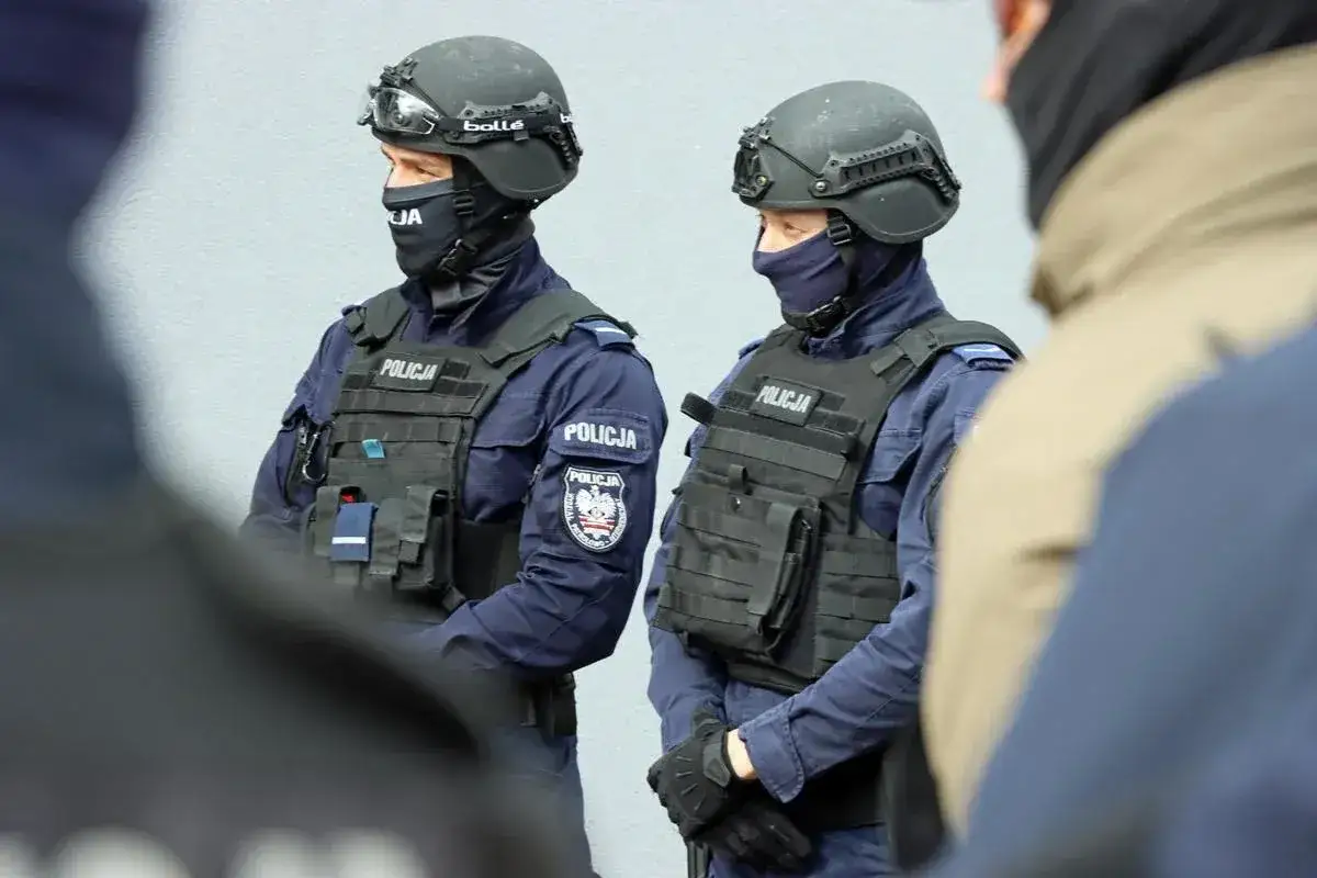 Dwóch policjantów w pełnym rynsztunku, z hełmami i kamizelkami taktycznymi, stanowi przykład profesjonalnej służby mundurowej.
