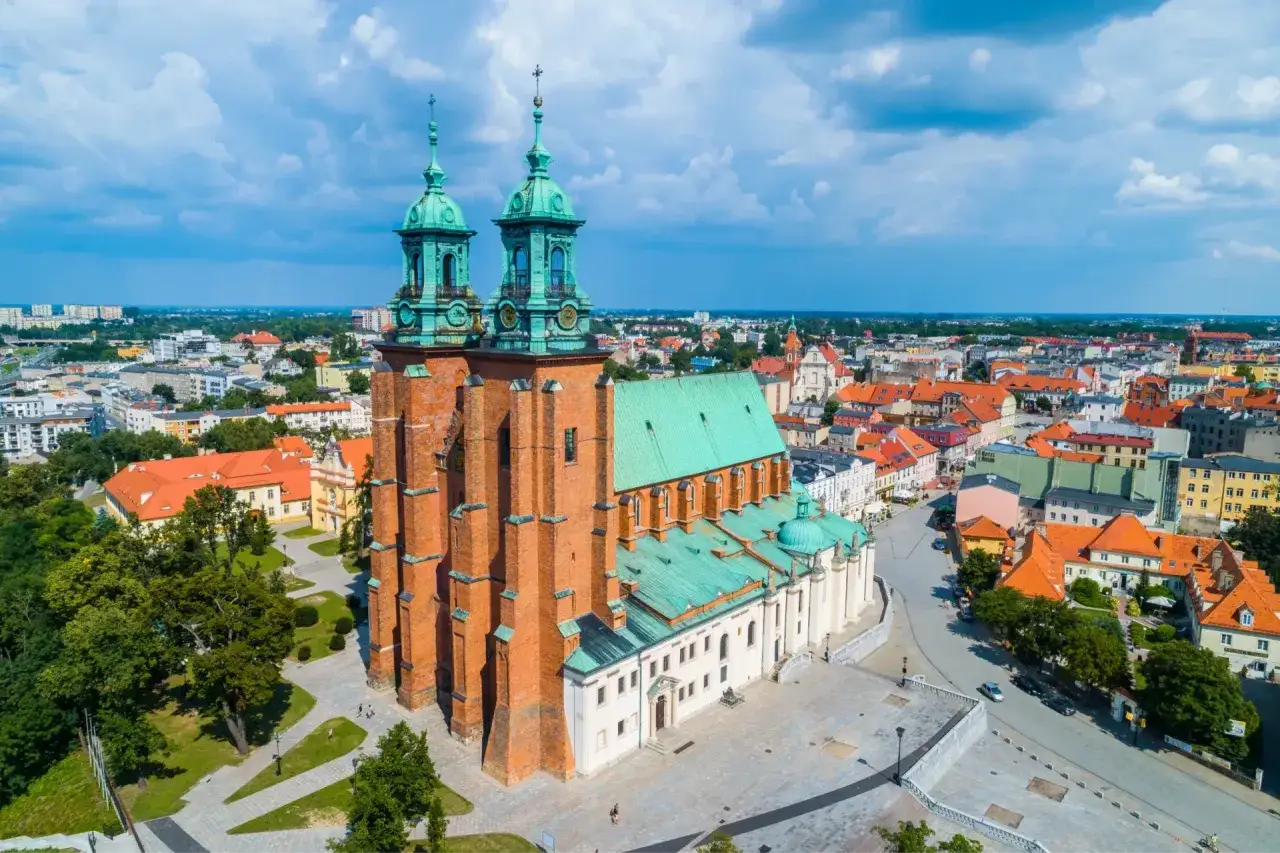 Imponująca katedra z zielonym dachem i dwiema wieżami, otoczona zabytkami w Polsce i miastem.