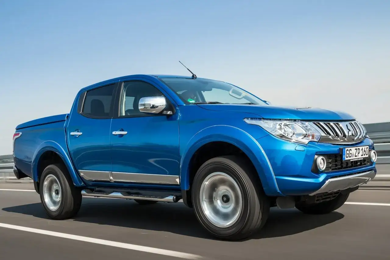 Niebieski pickup Mitsubishi L200 na drodze. To model z napędem 2WD, co znaczy, że napędza go jedna oś, idealny do miasta i na łatwiejsze trasy.