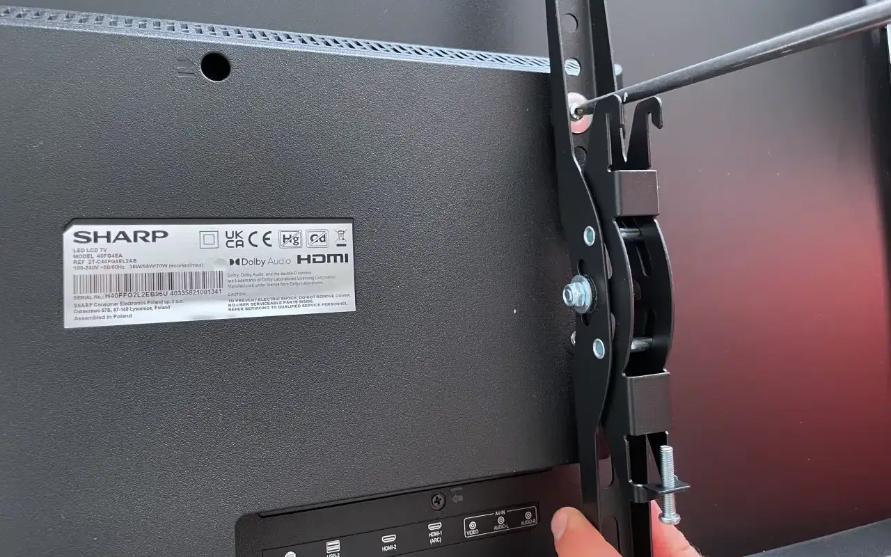 Montaż TV na ścianę: przykręcanie uchwytu do telewizora Sharp.