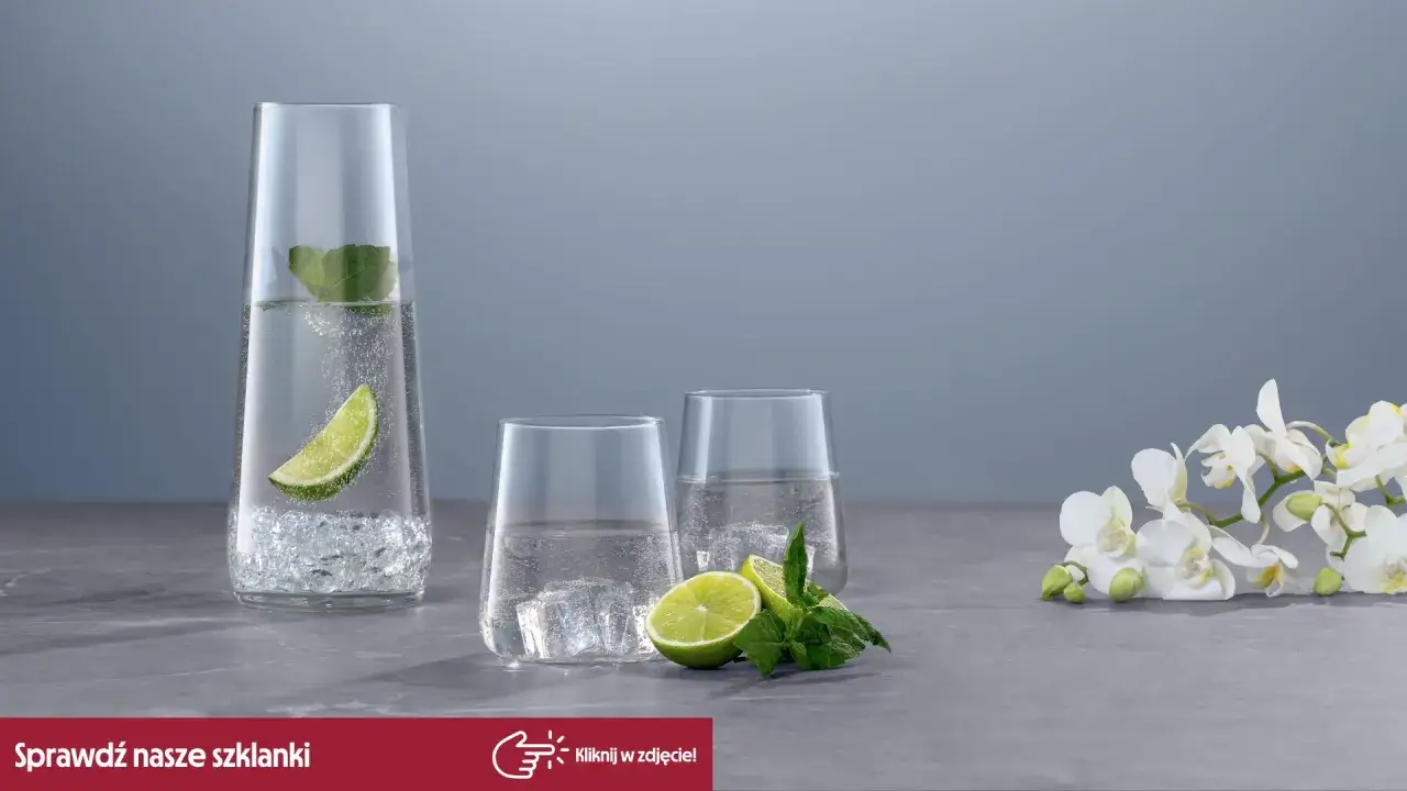 Eleganckie szklanki na drinki z lodem, limonką i miętą. Obok białe kwiaty.