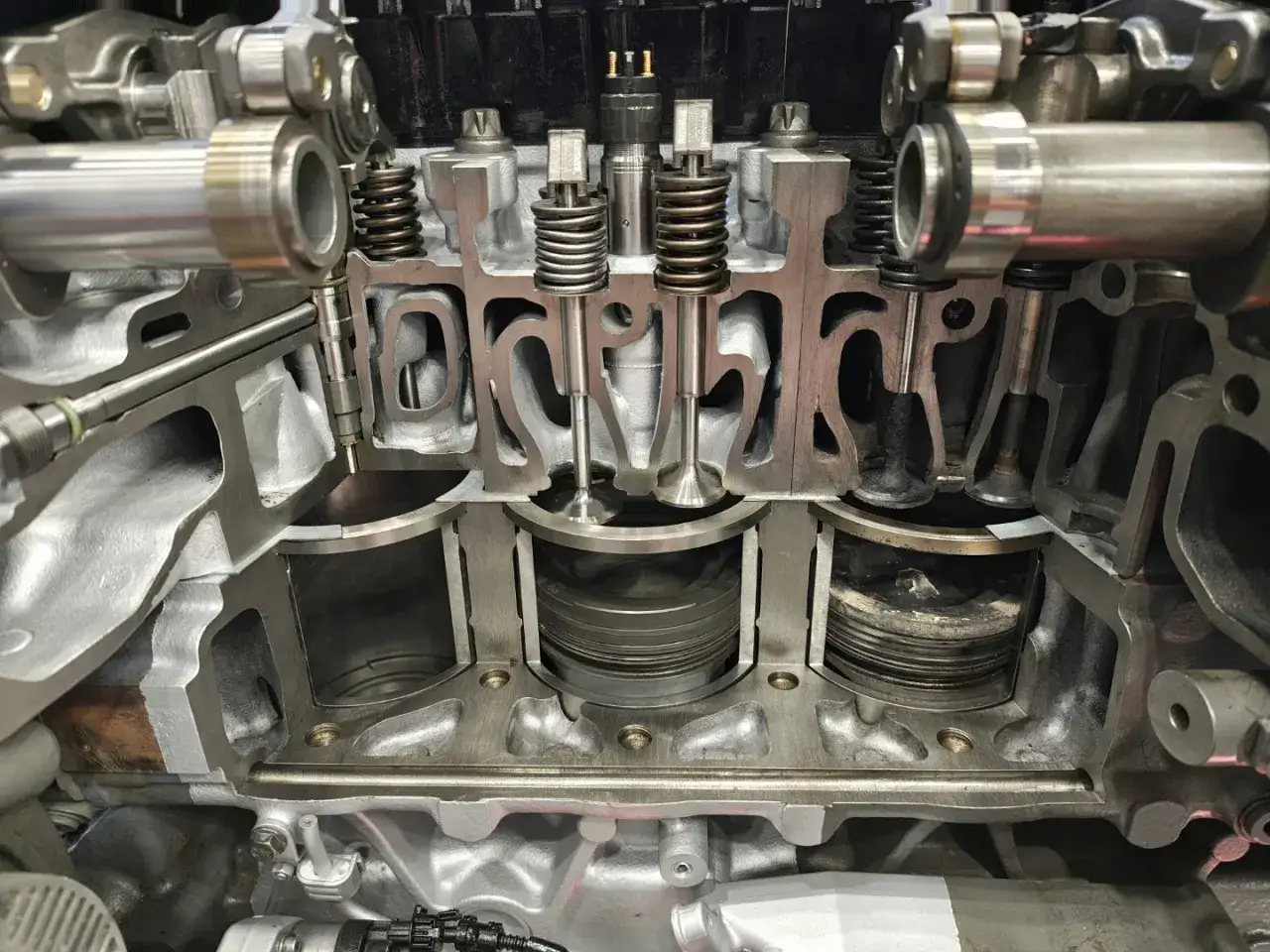 Przekrój silnika pokazuje, jak ustawić zawory. Widoczne są tłoki, sprężyny zaworowe i elementy układu paliwowego.