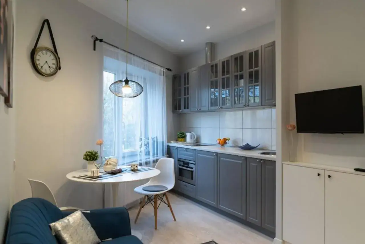 Jak urządzić małe mieszkanie 35 m: przytulna kuchnia z jadalnią, szare meble, okrągły stół, wygodna kanapa i telewizor.