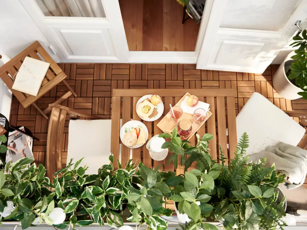 Uroczy mini balkon w bloku z drewnianym stolikiem, krzesłami i zielenią. Idealne miejsce na poranną kawę i śniadanie.