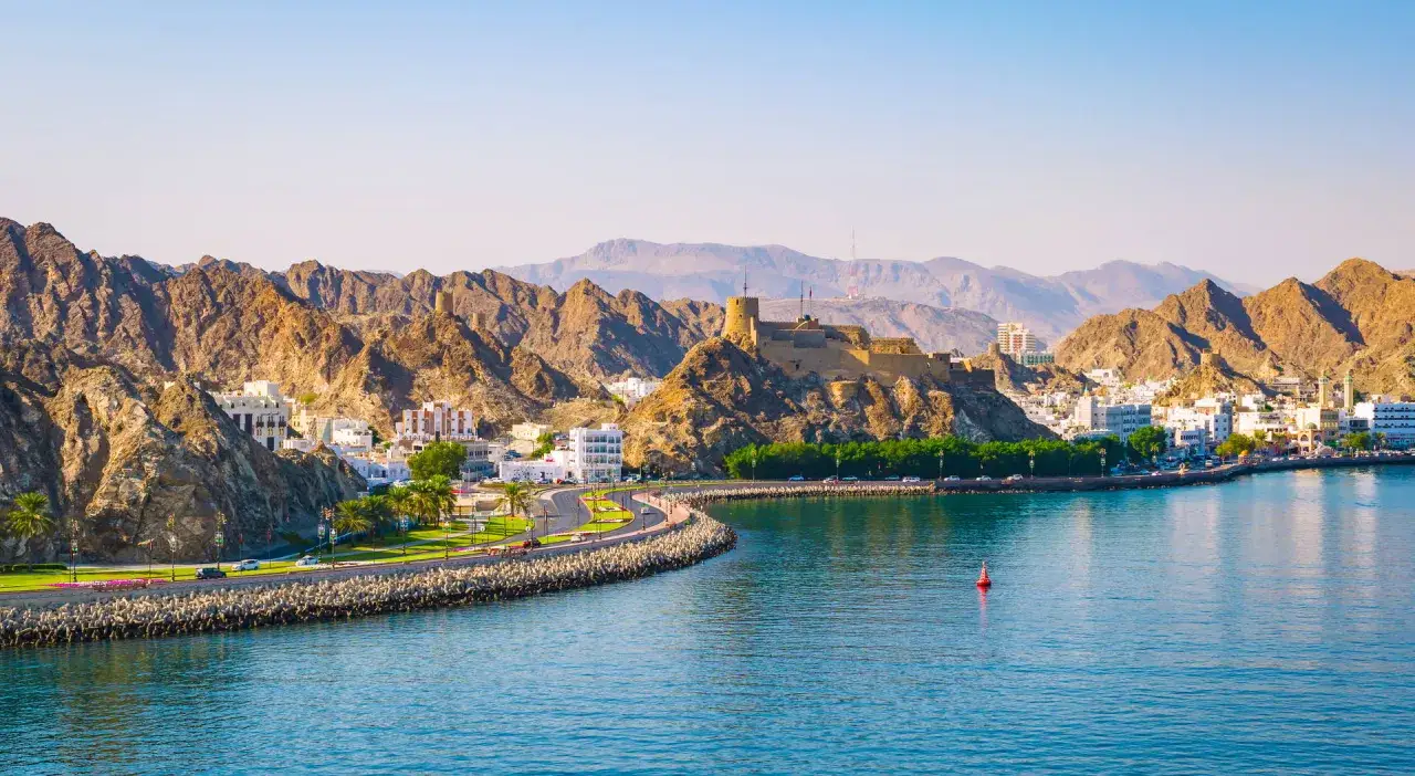 Widok na Muscat z górami w tle i fortecą na wzgórzu. Idealny czas, kiedy najlepiej lecieć do Omanu, to okres od października do kwietnia.