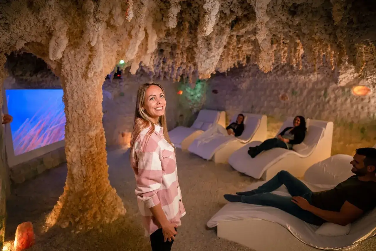Relaks w grocie solnej: wygodne ubranie to klucz do odprężenia. Kobieta w kratkę i inni odpoczywają na leżakach.