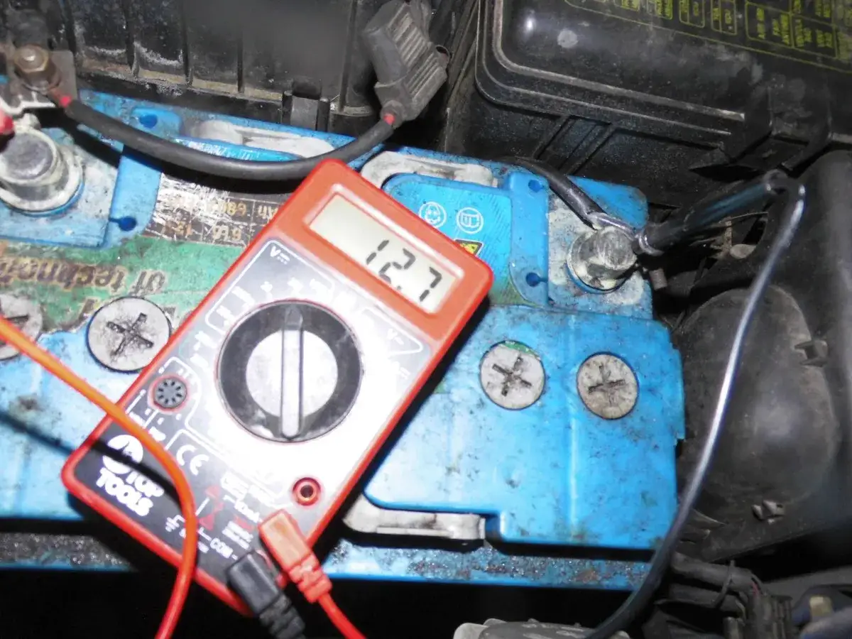 Multimetr pokazuje 12.7V na akumulatorze. Widać, że płyn w akumulatorze jest w dobrym stanie, a jego poziom jest odpowiedni.