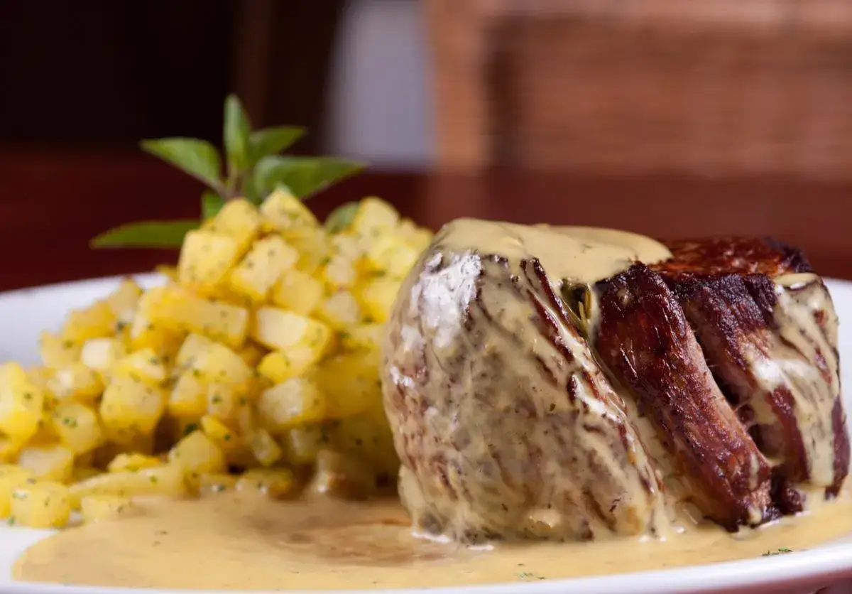 Soczysty stek polany kremowym sosem musztardowym, podany z chrupiącymi ziemniaczkami.