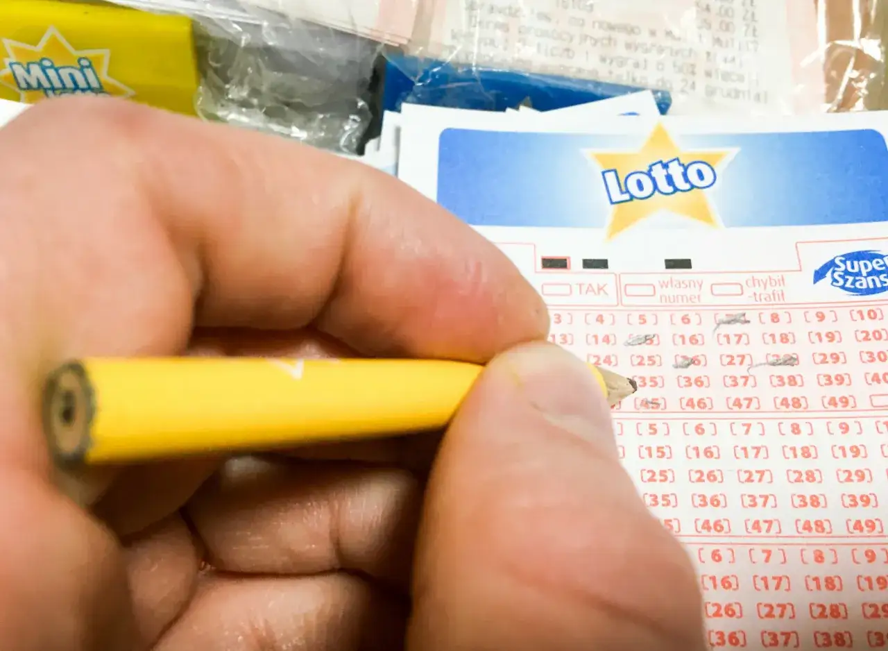 Dłoń z ołówkiem zaznacza liczby na kuponie Lotto. Czy w mini lotto występuje gwarantowana pula wygranych i kumulacja?