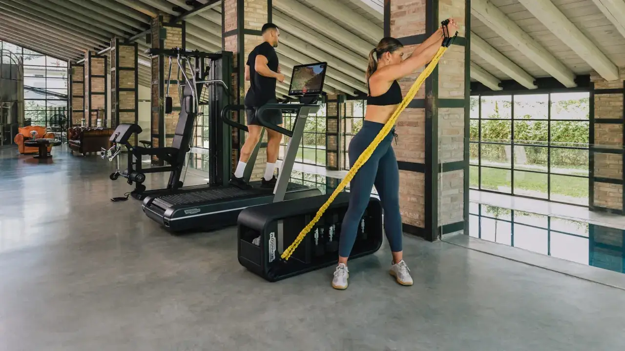 Kobieta ćwiczy z gumą, mężczyzna biegnie na bieżni. To przykład treningu funkcjonalnego, co to znaczy? Ćwiczenia poprawiające codzienne ruchy.