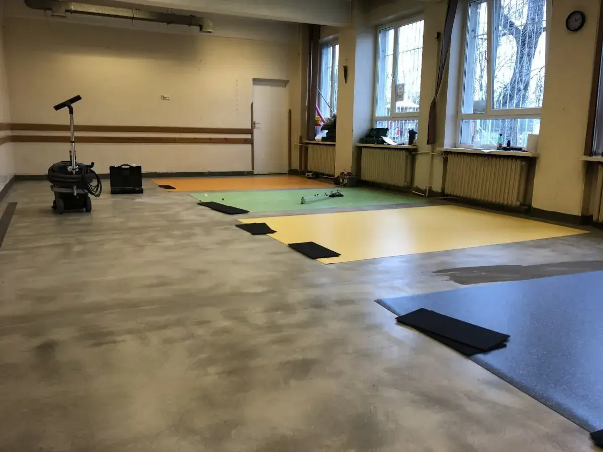 Układanie wykładziny pcv na panele. Kolorowe maty na podłodze sali gimnastycznej, przygotowane do montażu.