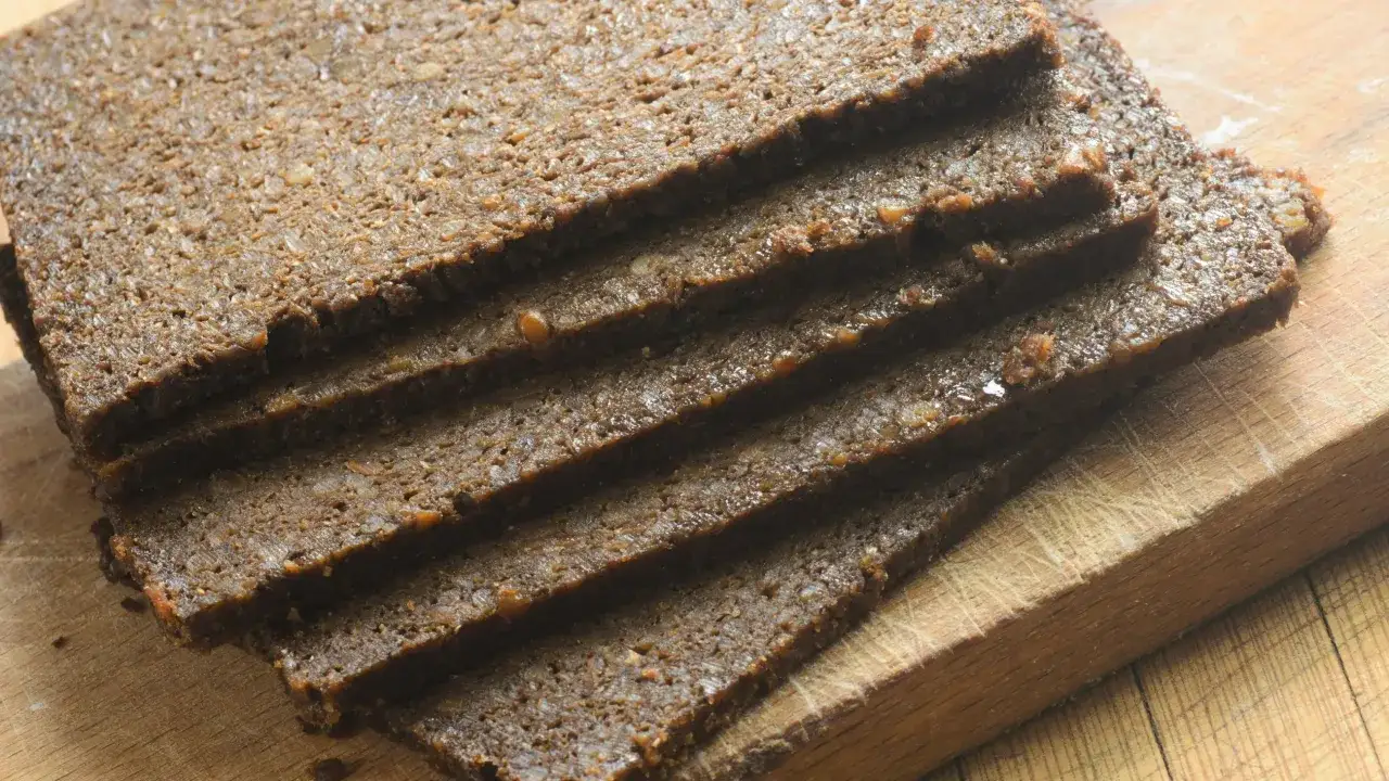 Kromki ciemnego pumpernikla ułożone na desce. Niska zawartość cukru sprawia, że pumpernikiel ma niski indeks glikemiczny.