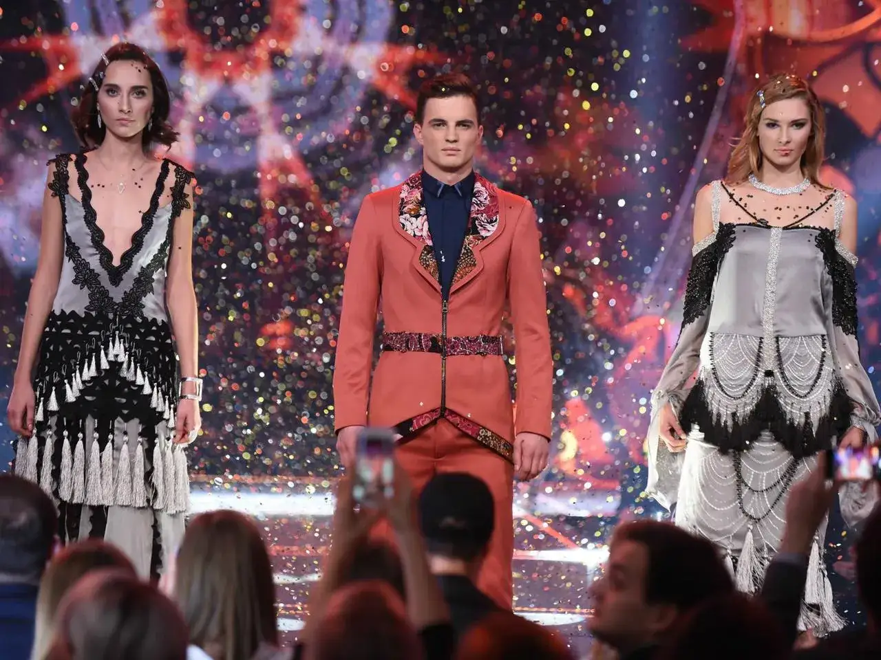 Trzech finalistów Top Model na scenie, w tle kolorowe konfetti.