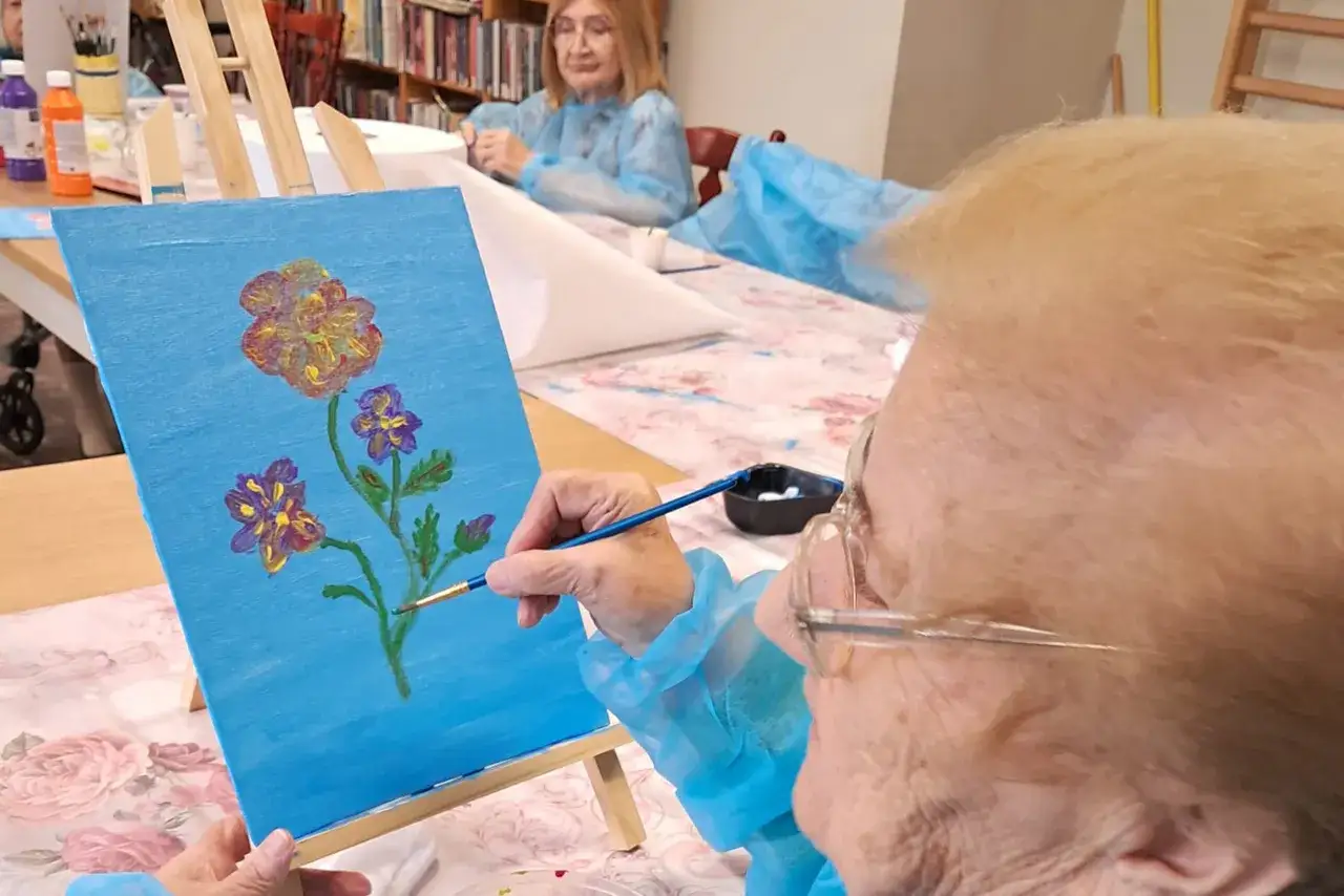 Osoba starsza maluje obraz farbami akwarelowymi
