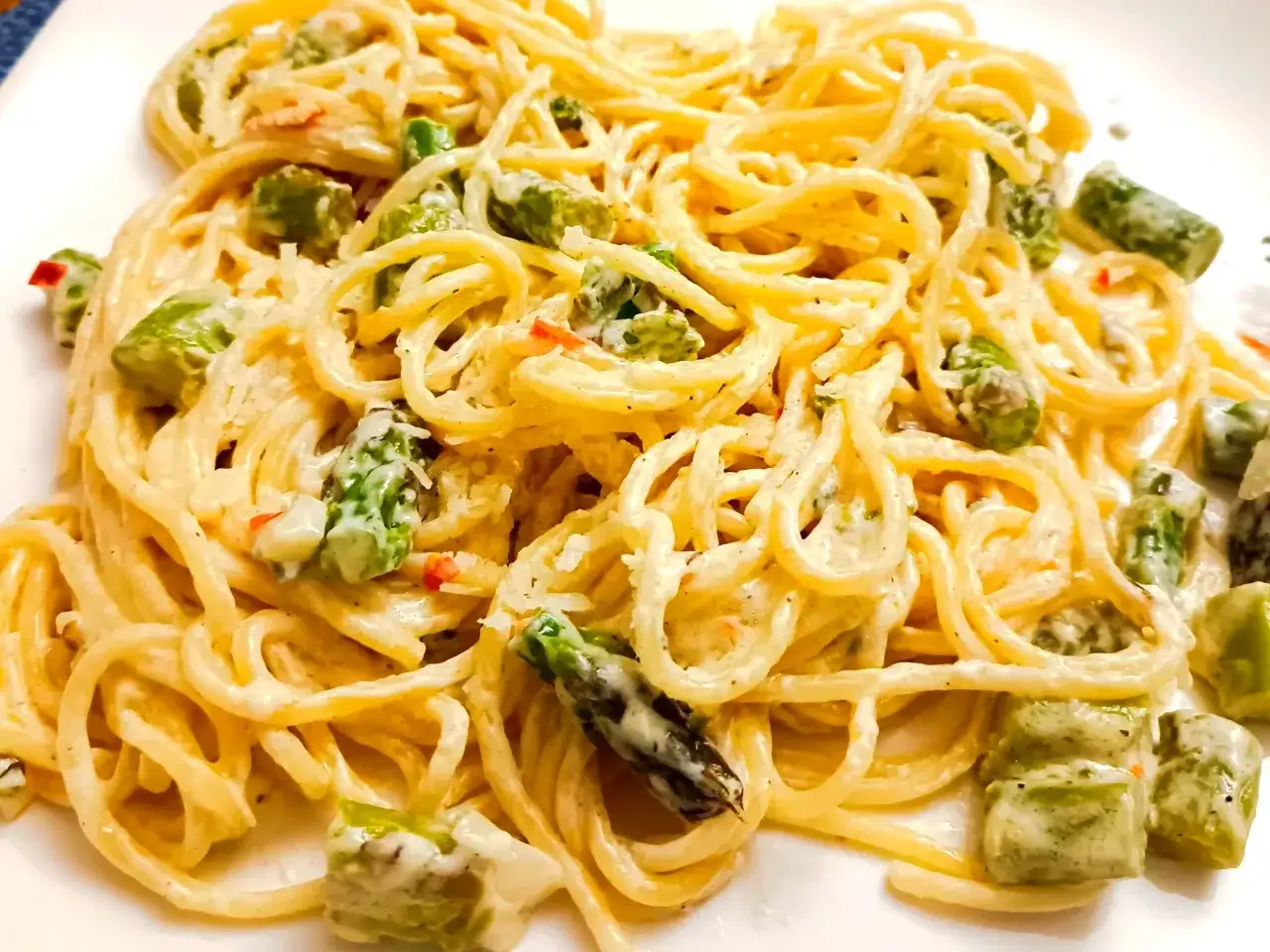 Pyszny makaron ze szparagami w kremowym sosie, posypany parmezanem. Idealne danie na wiosnę.