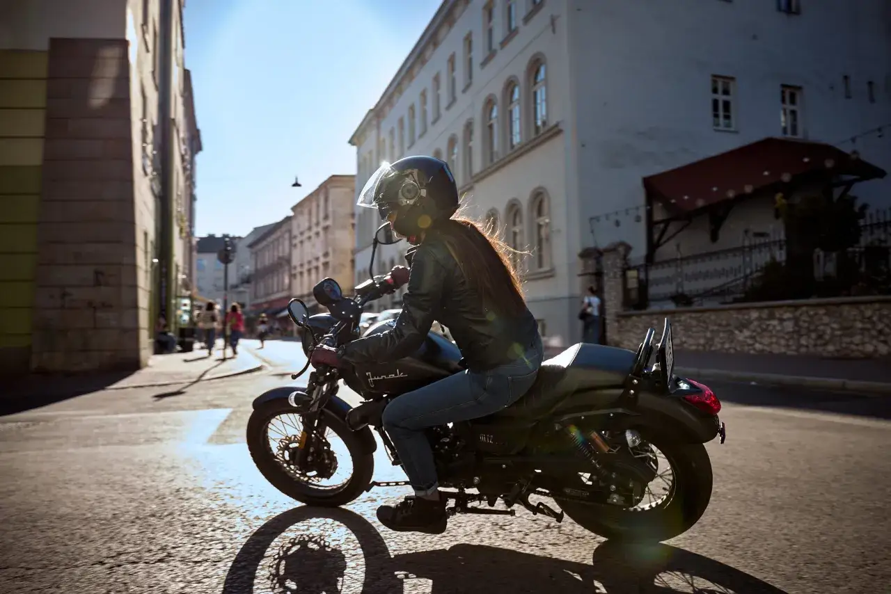Kobieta w kasku i sk&oacute;rzanej kurtce jedzie motocyklem po mieście. Zastanawiasz się, ile pali motocykl?