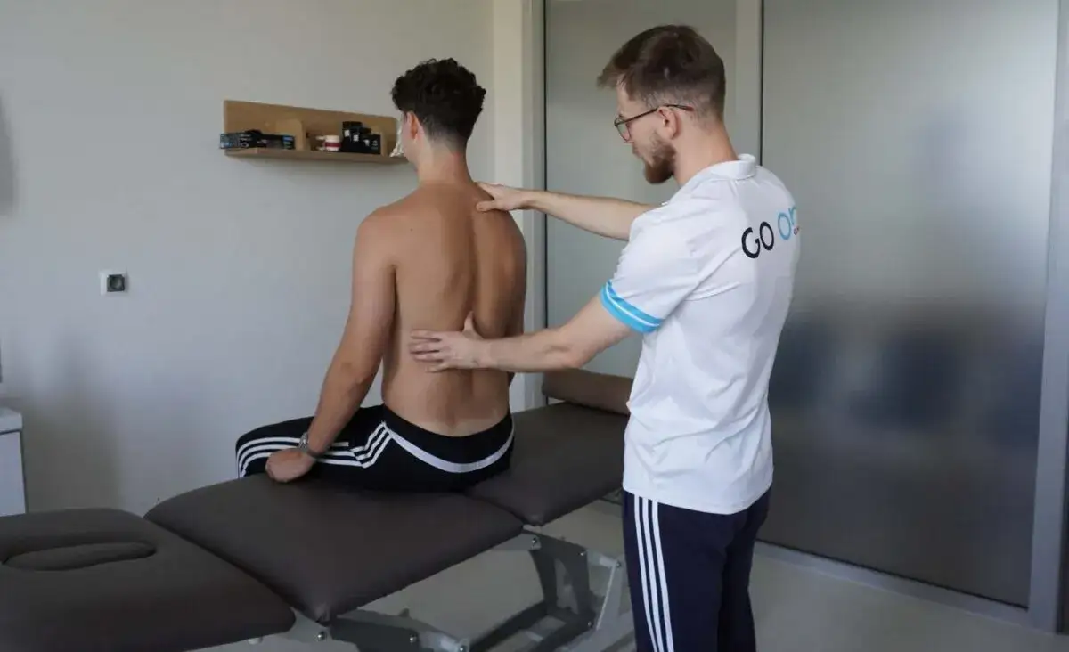 Fizjoterapeuta badający kręgosłup pacjenta w luźnym stroju