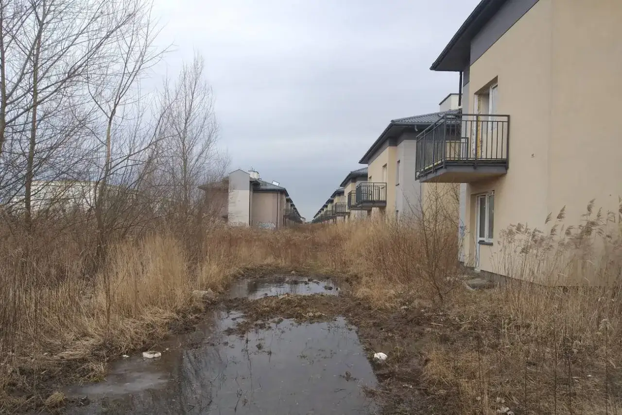 Zarośnięte osiedle z niedokończonymi budynkami, błoto i kałuże. Ukryte przyczyny bankructwa znanej firmy deweloperskiej z dużym bankiem ziemi?