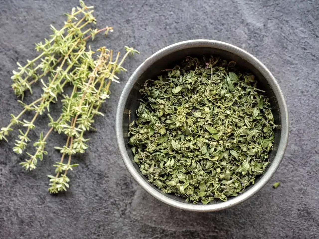 Świeże gałązki tymianku obok miseczki z suszonym zielem. Idealne do przygotowania aromatycznego naparu z tymianku.