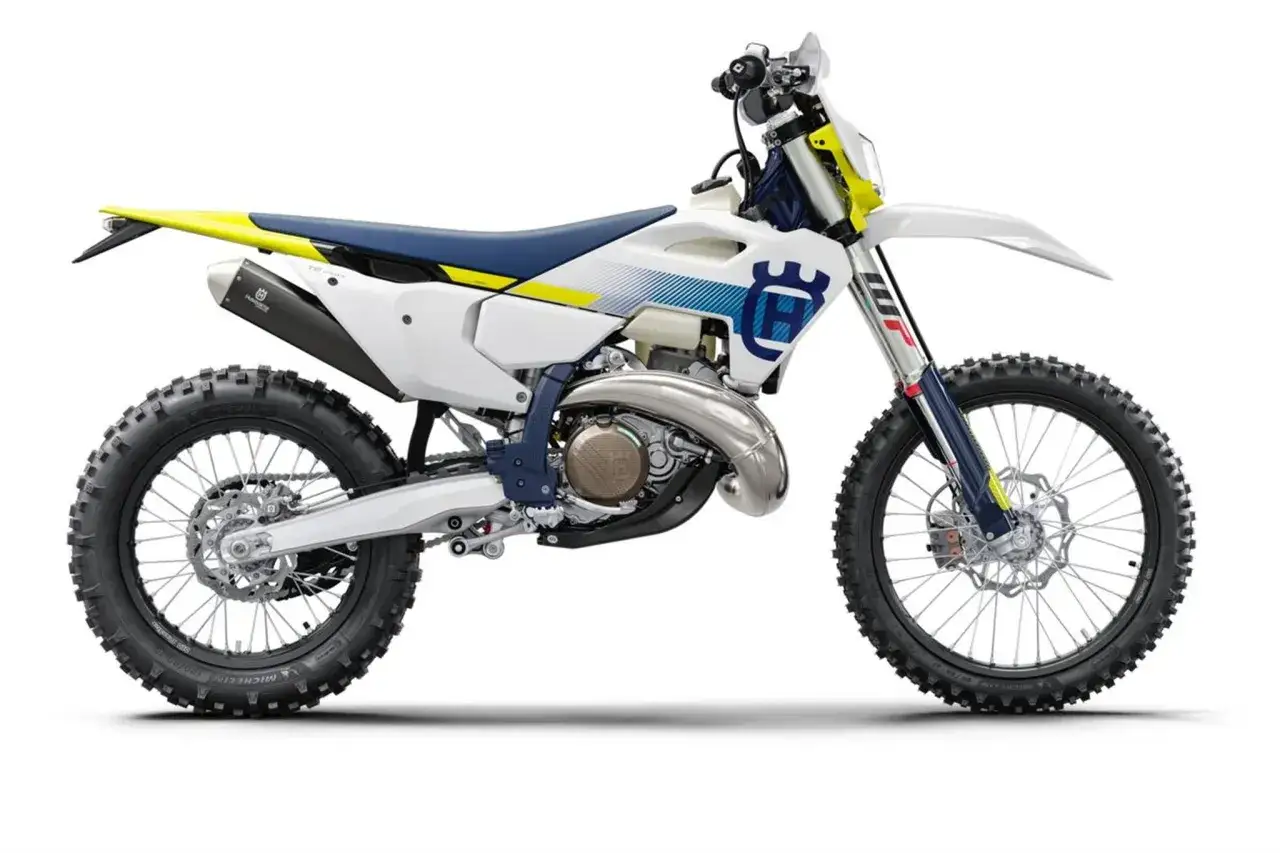 Husqvarna TE 250 gotowy do akcji. Biało-niebieski motocykl z ż&oacute;łtymi akcentami i terenowymi oponami.
